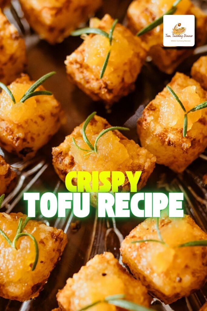 Golden crispy tofu cubes served on a white plate with a sprinkle of sesame seeds and fresh herbs, ready to eat.