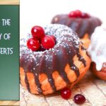 Close-up of two mini bundt cakes, one with chocolate icing and red berries, the other with white icing and red berries, placed on a woven mat. A hand points to a green chalkboard with the text "Exploring the Versatility of Fusion Desserts."