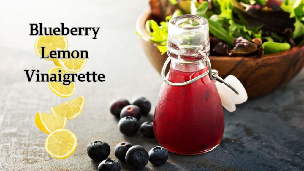 A bottle of blueberry lemon vinaigrette with fresh blueberries and lemon slices on the left, and a bowl of salad on the right.