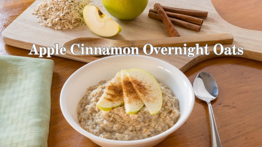 A bowl of apple cinnamon overnight oats on a wooden table, garnished with apple slices and a sprinkle of cinnamon.