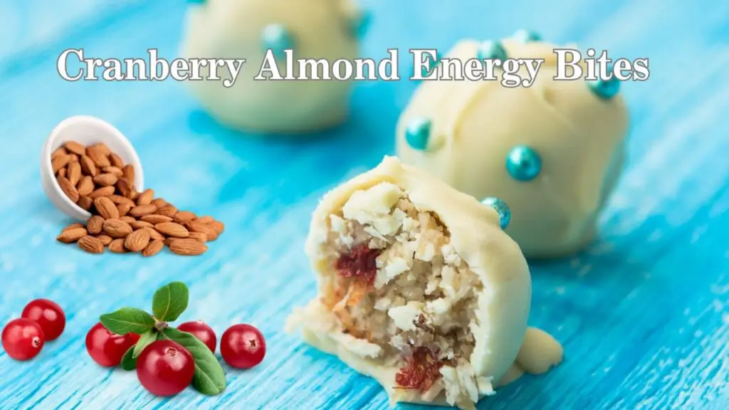 A vibrant image featuring homemade cranberry almond energy bites on a blue wooden surface. One energy bite is cut in half, revealing a textured filling with visible chunks of almonds and cranberries.