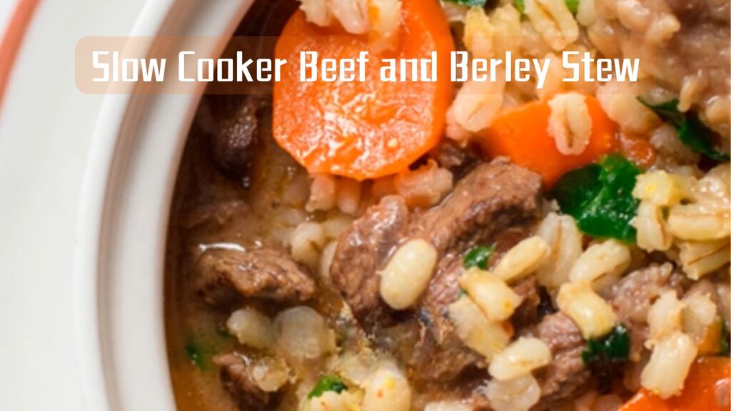 A close-up image of a hearty slow cooker beef and barley stew with chunks of beef, sliced carrots, and barley in a thick broth.