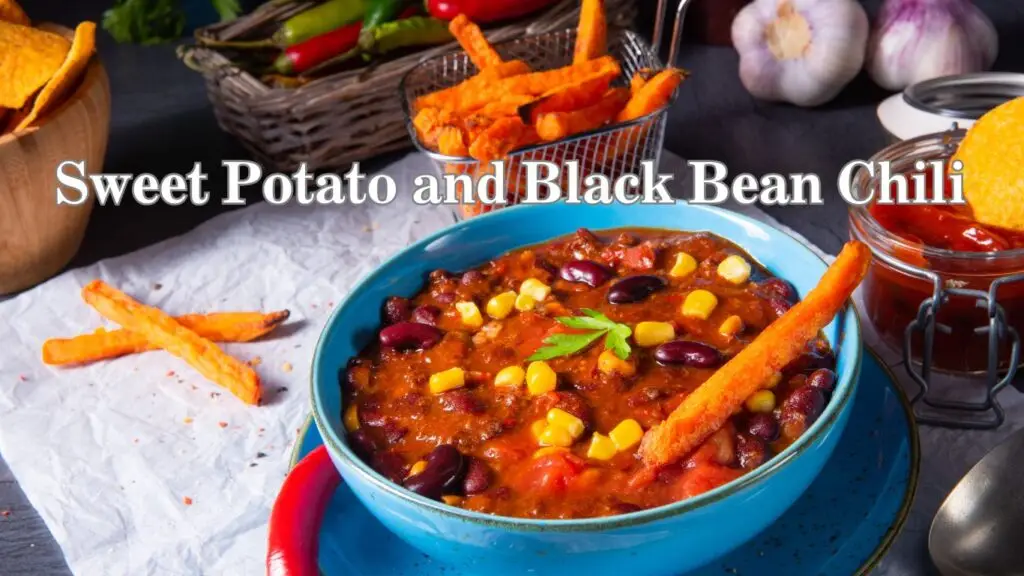 A vibrant photo of a bowl of sweet potato and black bean chili, garnished with a sweet potato fry and corn kernels, presented on a rustic table with ingredients in the background.