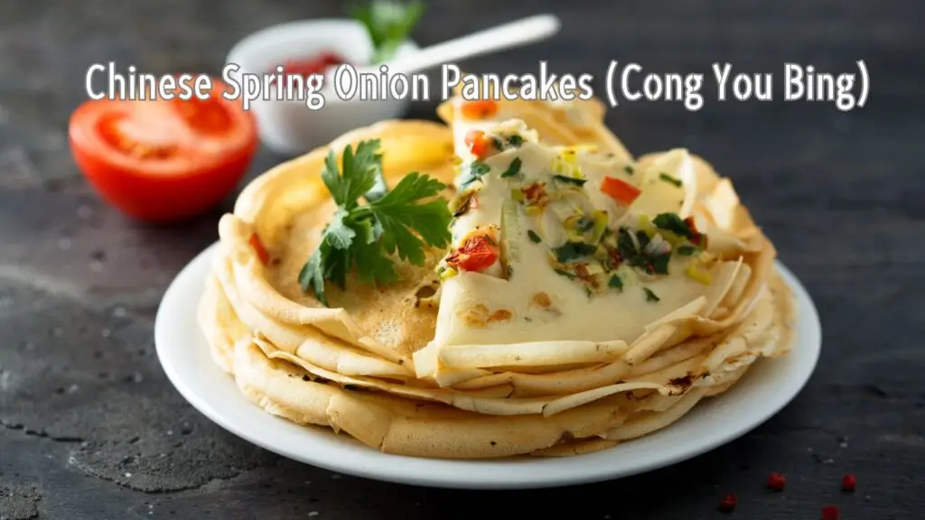 A stack of Chinese Spring Onion Pancakes (Cong You Bing) garnished with fresh herbs on a plate, with a sliced tomato in the background.