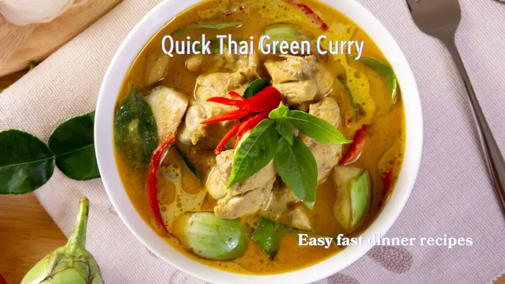 A bowl of Thai chicken curry garnished with red chilies and basil leaves.