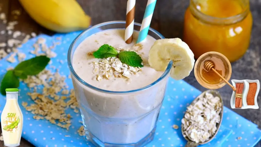 A glass of banana oat smoothie garnished with mint leaves, accompanied by ingredients like bananas, oats, honey, and soy milk.