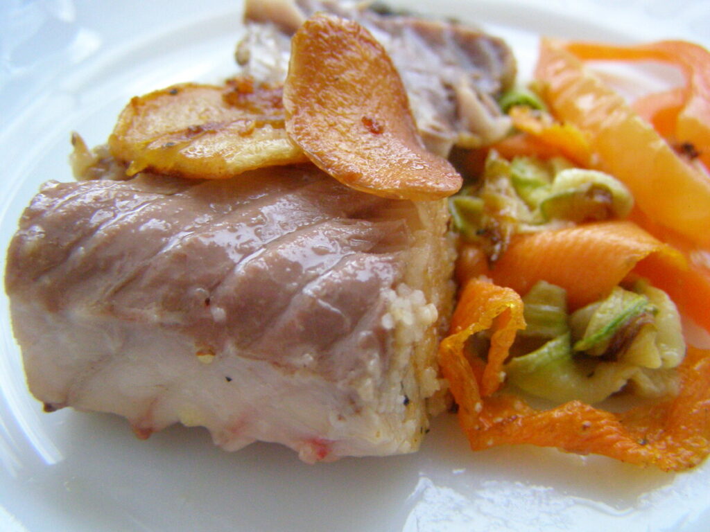 A close-up of fried-baked carp in sour cream, garnished with herbs and served with a side of sautéed vegetables.