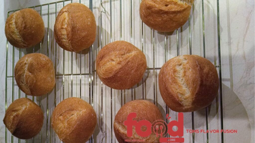 Freshly baked round bread rolls cooling on a wire rack