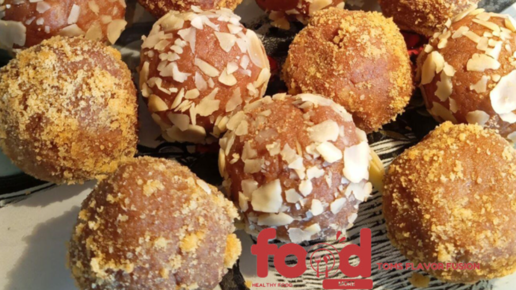 Close-up of several round, brown-colored dessert balls coated with crushed nuts and almond flakes.