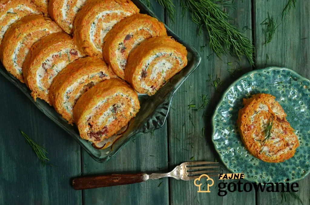 A savory carrot roulade sliced and served on a white plate, garnished with dried tomatoes and fresh herbs. The vibrant orange carrot roulade contrasts beautifully with the red tomatoes and green herbs.