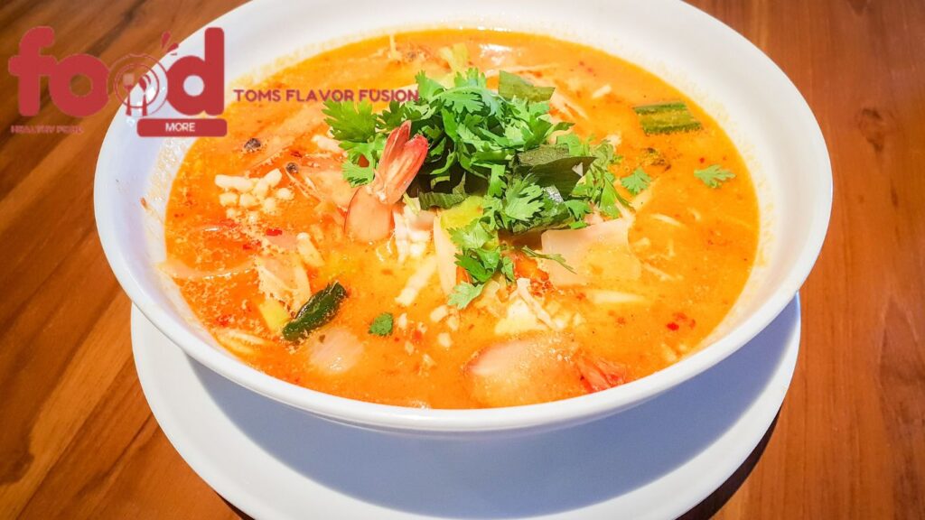 A bowl of Thai-style cod fish soup with curry, garnished with fresh herbs and served in a creamy coconut-based broth.