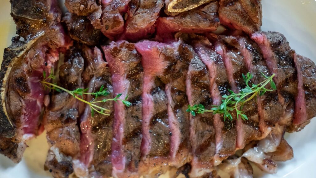 Sliced sous vide prime rib with a golden crust, garnished with fresh thyme sprigs.