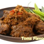 Traditional Pakistani beef curry served in a bowl, garnished with fried onions and fresh herbs.