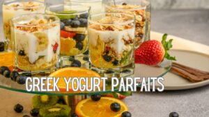 A display of Greek yogurt parfaits in clear glasses, layered with granola, fresh fruits like blueberries, strawberries, kiwi, and orange slices, with a honey drizzle on top. The text "GREEK YOGURT PARFAITS" is prominently displayed at the bottom of the image.