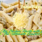 A plate of Marry Me Chicken Pasta with creamy sauce, penne pasta, and a topping of shredded cheese, garnished with fresh herbs.