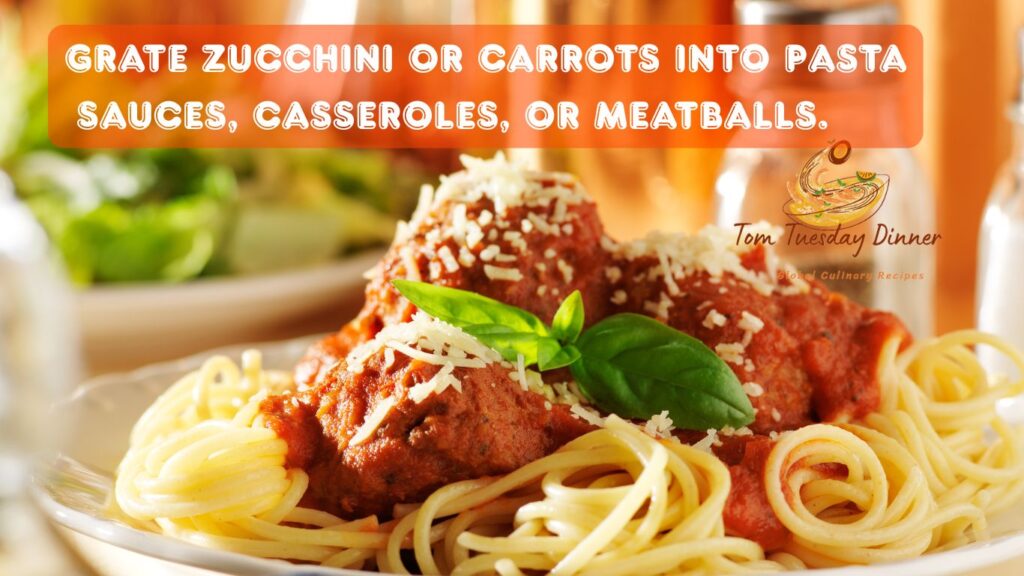 A plate of spaghetti with meatballs topped with grated cheese and a basil leaf, with a text overlay suggesting to grate zucchini or carrots into pasta sauces, casseroles, or meatballs.