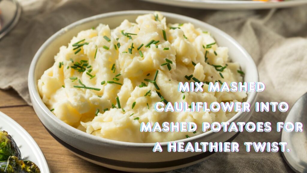 A bowl of mashed potatoes garnished with chopped chives, with a text overlay that reads "Mix mashed cauliflower into mashed potatoes for a healthier twist."