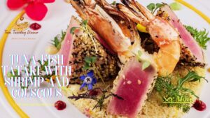 A gourmet dish featuring seared tuna tataki coated in sesame seeds, paired with plump grilled shrimp, served on a bed of fluffy couscous and garnished with fresh herbs and edible flowers.