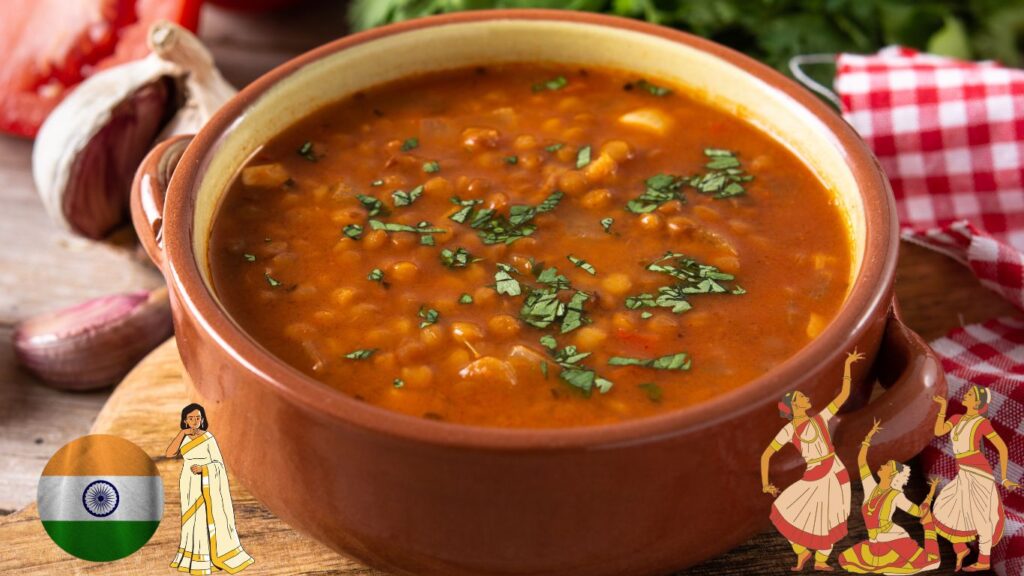 A bowl of Indian lentil soup garnished with fresh cilantro, placed on a wooden surface with garlic and shallots in the background. The image also includes an Indian flag, a woman in traditional attire, and illustrations of three women dancing.