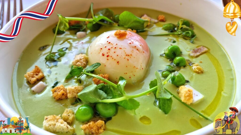 A bowl of green soup garnished with a poached egg, croutons, peas, and fresh greens.