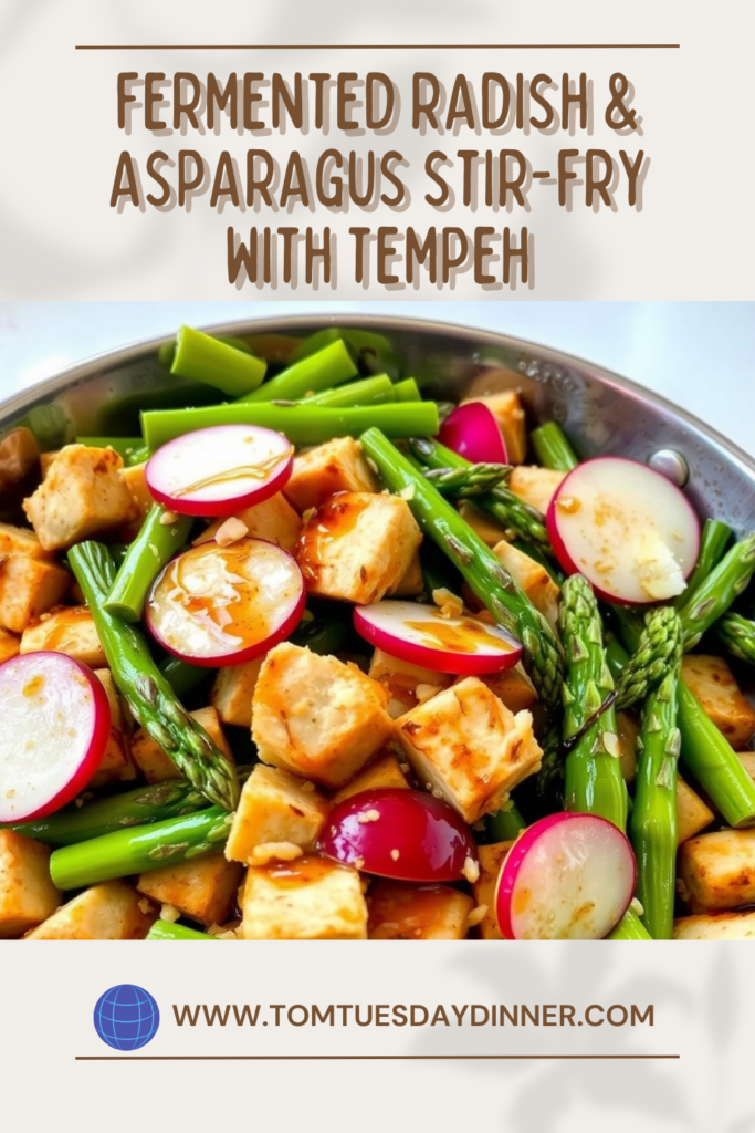 A vibrant stir-fry dish featuring fermented radish, asparagus, and tempeh, garnished with a savory sauce.