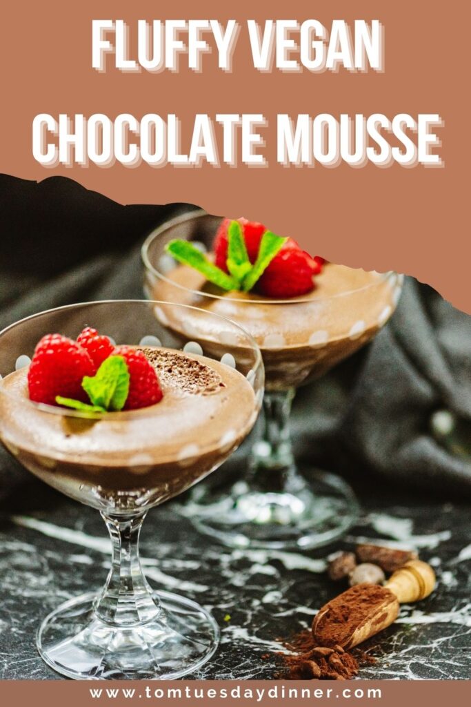 Fluffy vegan chocolate mousse topped with fresh raspberries and mint leaves in elegant glass cups, with a website link at the bottom.