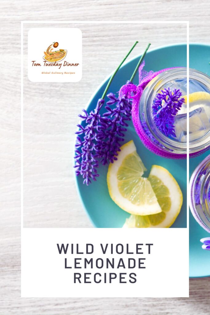 Overhead view of a blue plate with lemon slices and a jar of lemonade garnished with wild violet flowers. The text "Tom Tuesday Dinner Global Culinary Recipes" is at the top left, and "WILD VIOLET LEMONADE RECIPES" is at the bottom.